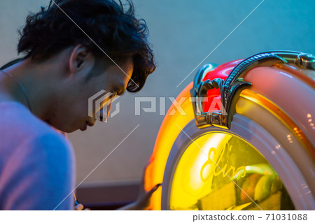 Young man operating a jukebox Young man operating a jukebox 71031088