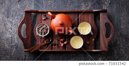 Green tea oolong in teapot and chawan bowls, cups on a wooden tray. Grey background. Top view. 71031542
