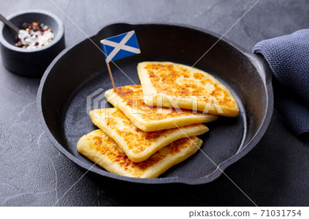 Traditional Scottish tattie potato scones in cast iron pan with Scotland flag. Dark background. Close up. 71031754
