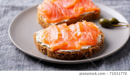 Sandwich, toast with smoked salmon and cream cheese on a plate. Grey background. Close up. Sandwich, toast with smoked salmon and cream cheese on a plate. Grey background. Close up. 71031778
