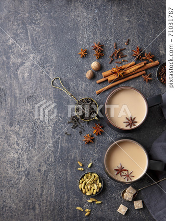 Indian masala tea with milk and spices in mug. Grey background. Copy space. Top view. Indian masala tea with milk and spices in mug. Grey background. Copy space. Top view. 71031787