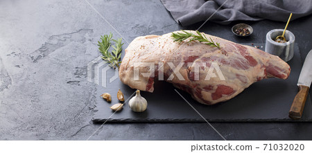 Raw lamb leg with spices and herbs on marble cutting board. Dark background. Copy space. Raw lamb leg with spices and herbs on marble cutting board. Dark background. Copy space. 71032020