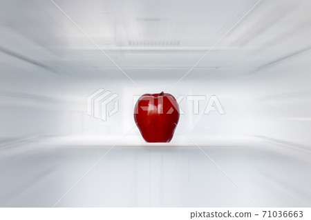 A lone red apple on a shelf in an empty fridge. A lone red apple on a shelf in an empty fridge. 71036663