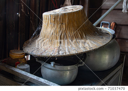 Asian straw hat on a dishware. Old things in a house at Thai countryside. Asian straw hat on a dishware. Old things in a house at Thai countryside. 71037470