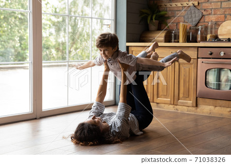 Young Caucasian mom engaged in funny game with small son 71038326