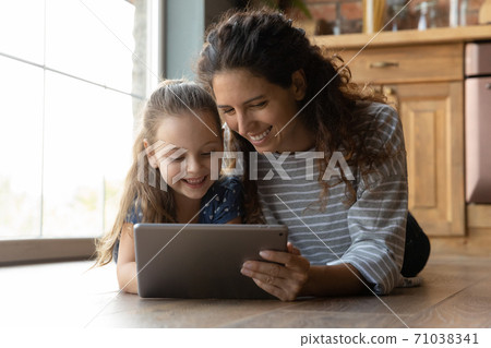 Happy mom and small daughter using tablet together Happy mom and small daughter using tablet together 71038341