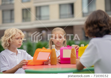 Children having lunch together and looking thoughtful Children having lunch together and looking thoughtful 71039152
