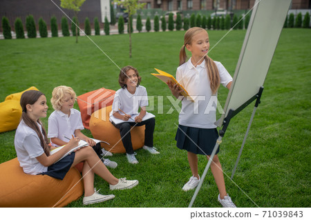 Fair-haired girl standing near the flipchart and looking thoughtful 71039843