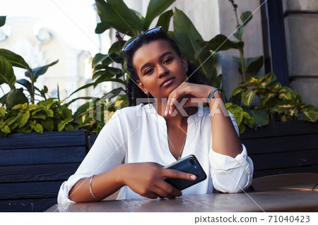 young pretty african girl posing cheerful in cafe outdoor, lifestyle people concept 71040423