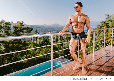 Fashion Portrait Of A Muscular Man In swim trunks At Swimming Pool Fashion Portrait Of A Muscular Man In swim trunks At Swimming Pool 71040607