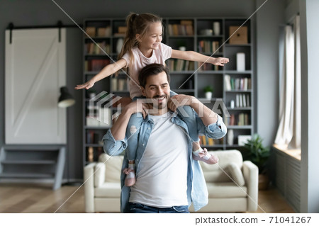 Happy young man holding on shoulders playful little preschool daughter. 71041267