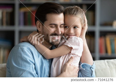 Affectionate young man cuddling cute small preschool kid daughter. Affectionate young man cuddling cute small preschool kid daughter. 71041276
