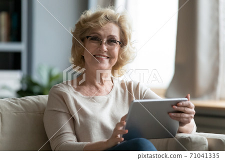 Portrait of beautiful smiling elderly woman using digital tablet. 71041335