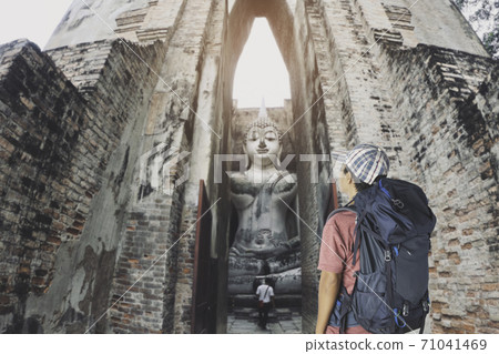 man with backpack looking old buddha in the temple at Sukhothai province. man with backpack looking old buddha in the temple at Sukhothai province. 71041469