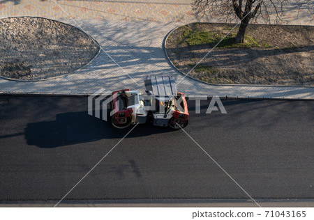Asphalt road roller with heavy vibration roller compactor press new hot asphalt on the roadway on a road construction site. Heavy Vibration roller at asphalt pavement working. Repairing. 71043165