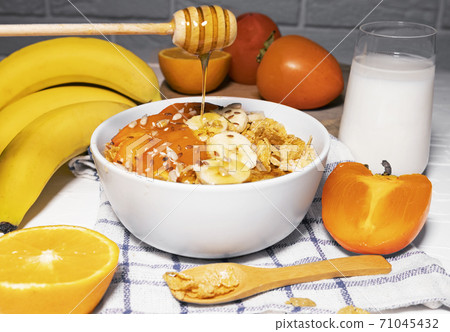 Corn Flakes Bowl with Banana, Milk, Persimmon, Orange and Honey on white background, Healthy Breakfast 71045432