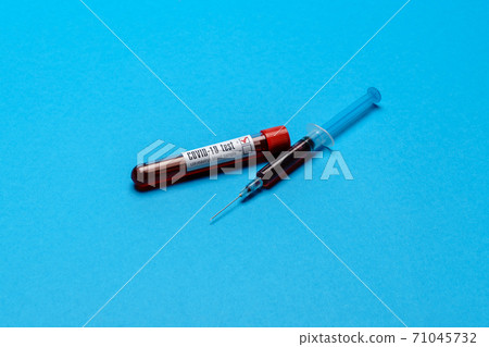 Syringe And Plastic Test Tube With Blood Sample over blue background with copyspace Syringe And Plastic Test Tube With Blood Sample over blue background with copyspace 71045732