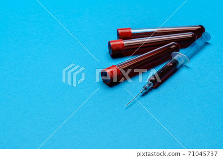Syringe And Plastic Test Tube With Blood Sample over blue background with copyspace Syringe And Plastic Test Tube With Blood Sample over blue background with copyspace 71045737