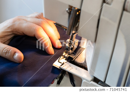 seamstress processes the edge of fabric on serger 71045741