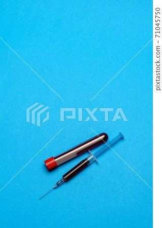 Syringe And Plastic Test Tube With Blood Sample over blue background with copyspace 71045750