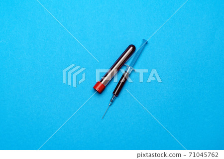 Syringe And Plastic Test Tube With Blood Sample over blue background with copyspace Syringe And Plastic Test Tube With Blood Sample over blue background with copyspace 71045762