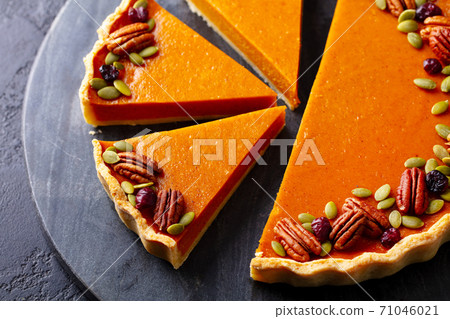 Pumpkin pie, tart with pecan nuts on black marble cutting board. Close up. 71046021