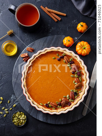 Pumpkin pie on marble board with cup of tea. Grey background. Close up. Top view. 71046025