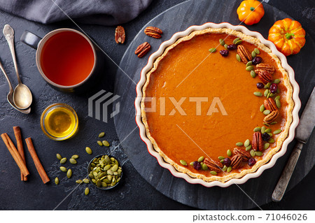 Pumpkin pie on marble board with cup of tea. Grey background. Close up. Top view. 71046026