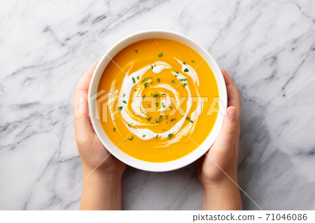 Kids hands holding a bowl with pumpkin soup. Marble background. Top view. Kids hands holding a bowl with pumpkin soup. Marble background. Top view. 71046086