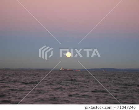 The gradation sky of the setting sun and the full moon rising from the sea 71047246