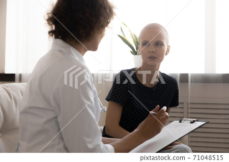 Close up doctor writing hairless woman complaints, filling patient card 71048515