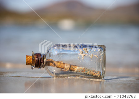 Message in the bottle against the Sun setting down 71048768