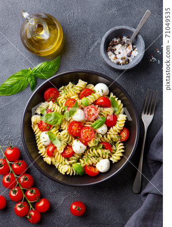 Pasta fusilli with mozzarella cheese, tomatoes and basil. Grey background. Top view. 71049535
