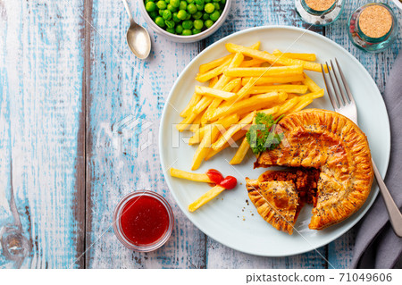 Meat pie with french fries on a white plate. Wooden background. Copy space. Top view. 71049606