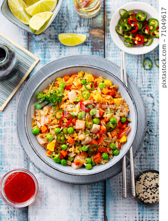 Asian fried rice with vegetables and ham. Blue wooden background. Copy space. Top view. Asian fried rice with vegetables and ham. Blue wooden background. Copy space. Top view. 71049617