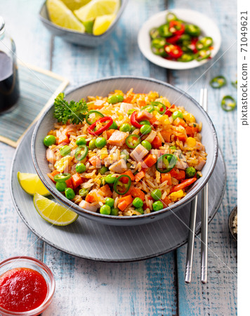 Asian fried rice with ham and vegetables. Blue wooden background. Close up. Asian fried rice with ham and vegetables. Blue wooden background. Close up. 71049621