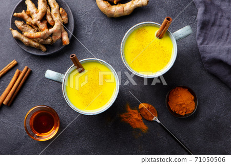 Turmeric drink, latte, tea, milk with cinnamon in a mug with fresh and powder turmeric. Dark background. Top view. 71050506