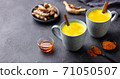 Turmeric drink, latte, tea, milk with cinnamon in a mug with fresh and powder turmeric. Grey background. Copy space. 71050507