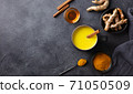 Turmeric drink, latte, tea, milk with cinnamon in a mug with fresh and powder turmeric. Dark background. Copy space. Top view. 71050509
