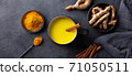 Turmeric drink, latte, tea, milk with cinnamon in a mug with fresh and powder turmeric. Dark background. Top view. 71050511