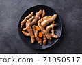 Fresh turmeric, curcumin, tumeric roots on a black plate. Superfood product. Dark background. Close up. Top view. 71050517