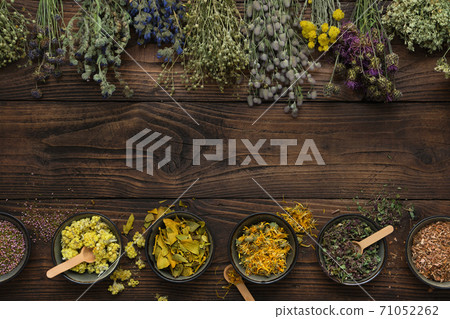 Medicinal plants bunches and row of bowls with dry medicinal herbs on brown wooden board. Top view, flat lay. Alternative medicine. 71052262