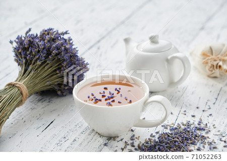 Healthy lavender herbal tea cup, dry lavender flowers and tea kettle on white wooden table. 71052263