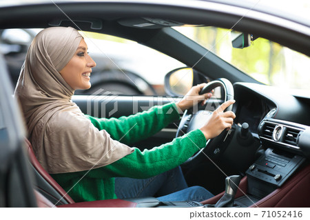 Smiling muslim woman test driving new car in urban city 71052416