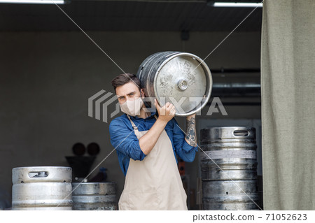 Young man working at warehouse in brewery or employee with keg 71052623