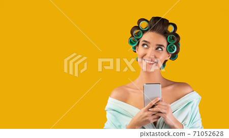 Cheerful Housewife With Smartphone Looking Aside Posing Over Yellow Background Cheerful Housewife With Smartphone Looking Aside Posing Over Yellow Background 71052628