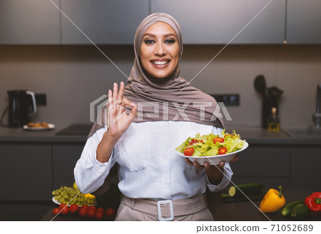 Arab Lady Cooking Standing In Kitchen, Holding Salad Gesturing OK 71052689