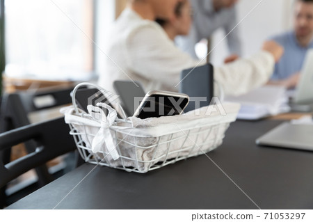 Close up basket with electronic gadgets smartphones standing on table. 71053297