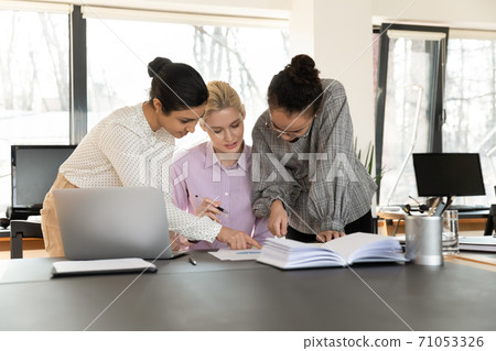 Concentrated young diverse multiracial female colleagues analyzing paper report. 71053326