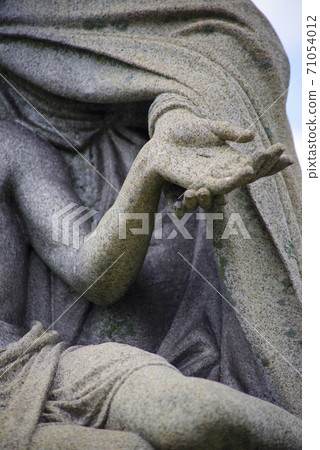 Close up of Mary holding Jesus's hand with stigmata in cemetery statue. 71054012